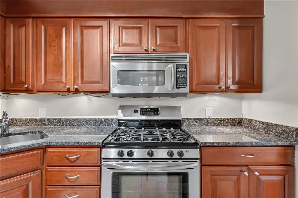 Stainless steel range, stainless steel microwave, stone countertops, and wood cabinetry