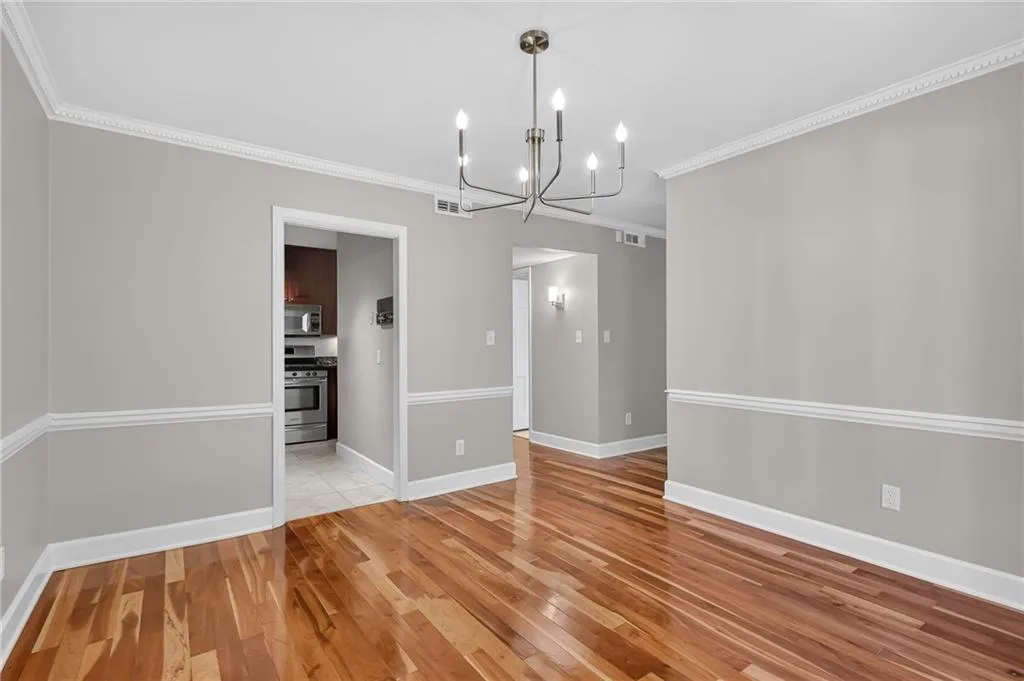 Hardwood flooring, crown molding, chair rail, and modern chandelier