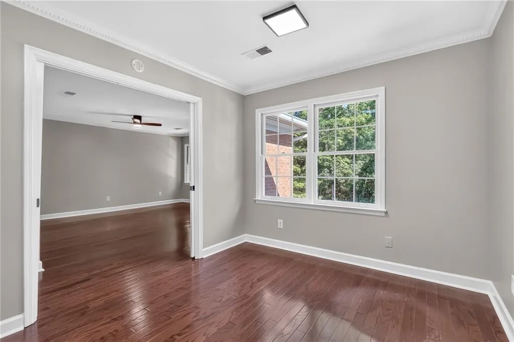 Hardwood flooring, crown molding, white trim, square recessed lighting, and a large window