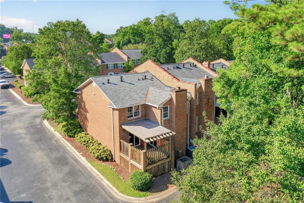 Brick exterior, multi-level deck with a wood pergola, asphalt shingle roofing, and mature trees