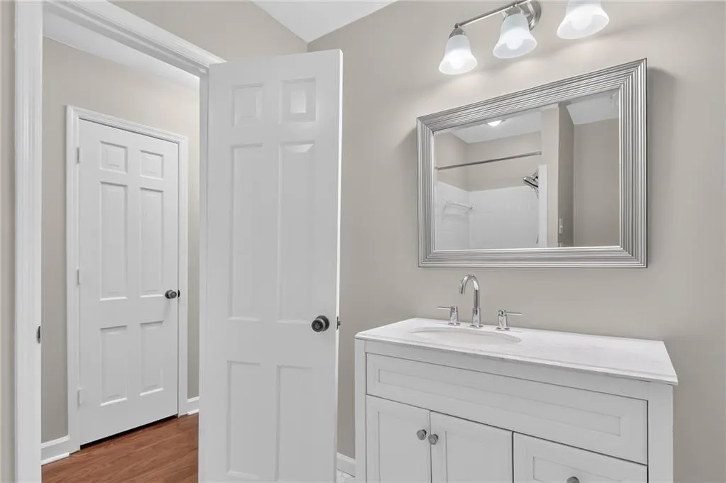 White vanity with integrated sink, chrome faucet, and framed mirror