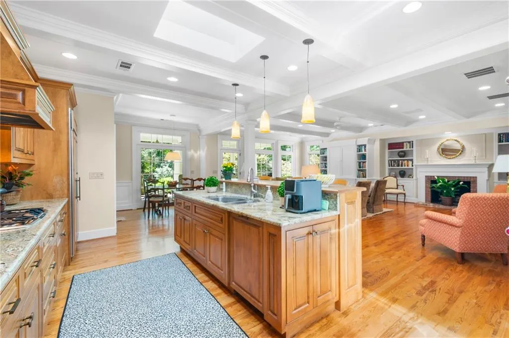 Kitchen featuring  hardwood flooring, sink, crown molding, a brick fireplace, and a large island