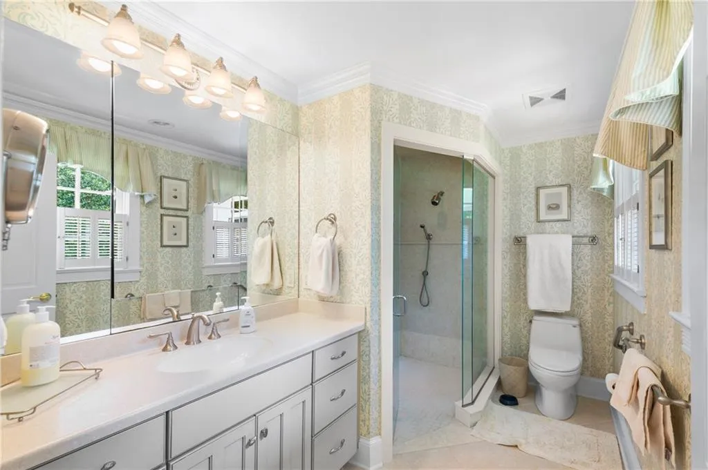 Bathroom featuring tile patterned flooring, crown molding, an enclosed shower, toilet, and vanity