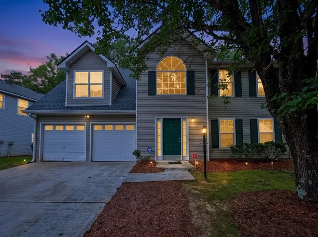 Two-story residence featuring light gray siding, a two-car garage, and a prominent arched window