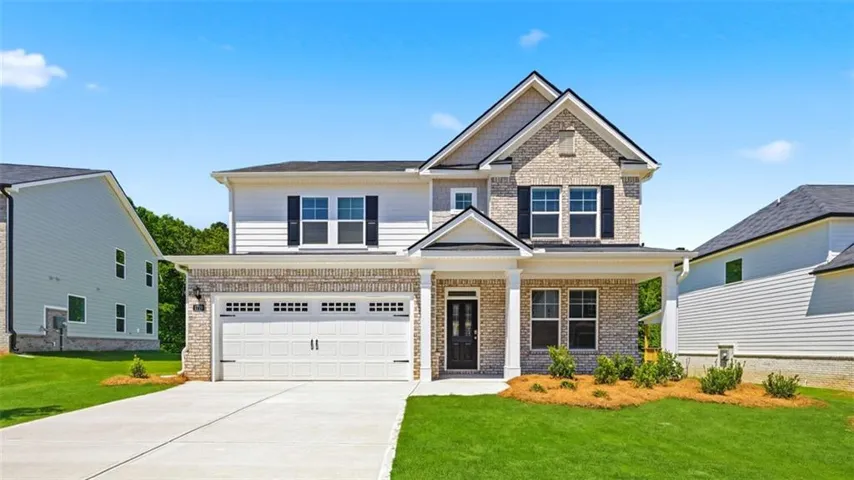 Two-story residence featuring a brick and siding exterior, a two-car garage, and a covered front entry with columns