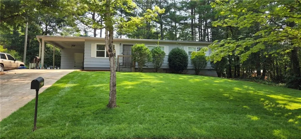 Light blue siding exterior with white window trim and shutters, featuring a covered carport