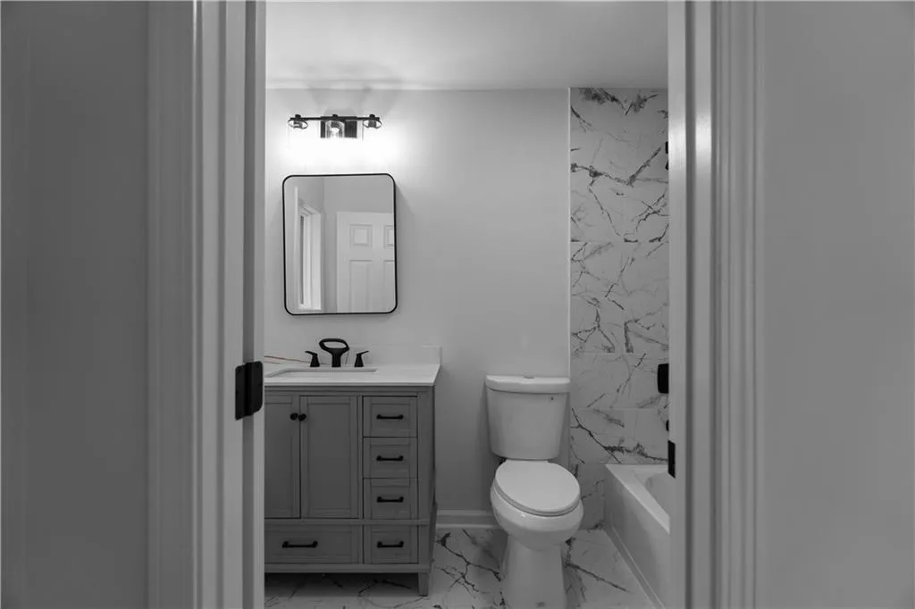 Full bathroom with vanity, tiled shower / bath combo, and toilet
