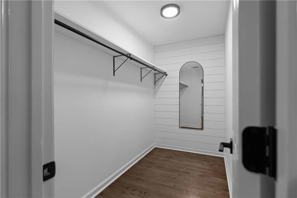 Walk in closet with dark hardwood / wood-style flooring