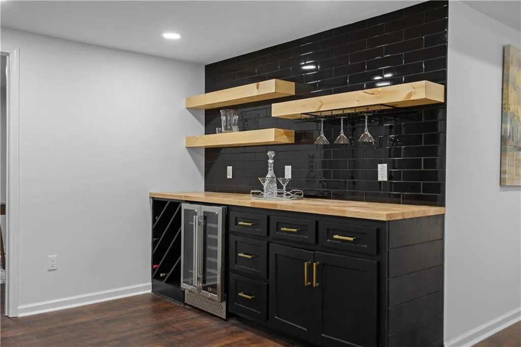 Bar featuring butcher block countertops, dark hardwood / wood-style floors, beverage cooler, and backsplash