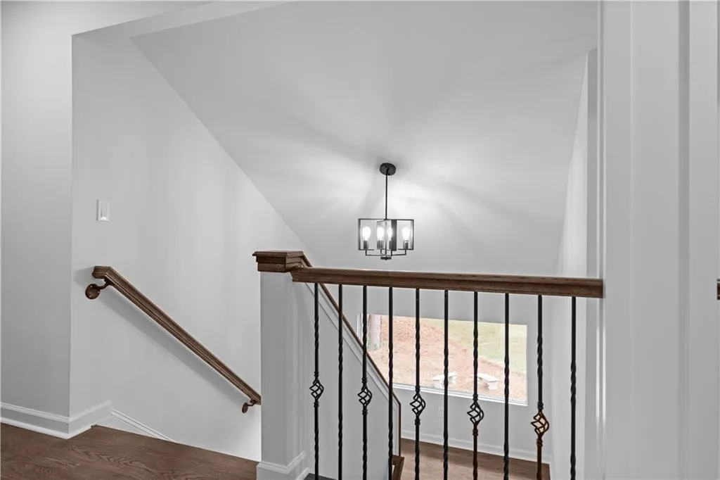 Stairway with hardwood / wood-style flooring and an inviting chandelier