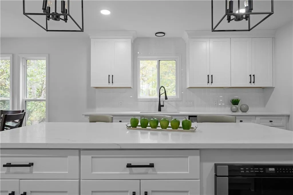 Kitchen featuring white cabinets, a healthy amount of sunlight, sink, and tasteful backsplash