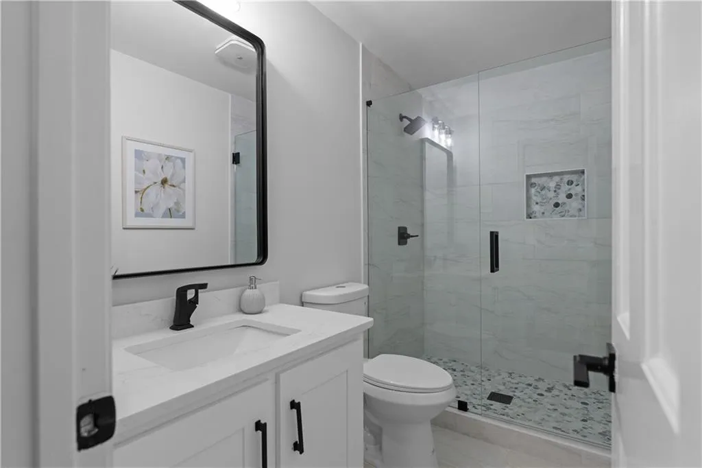 Bathroom featuring an enclosed shower, vanity, and toilet