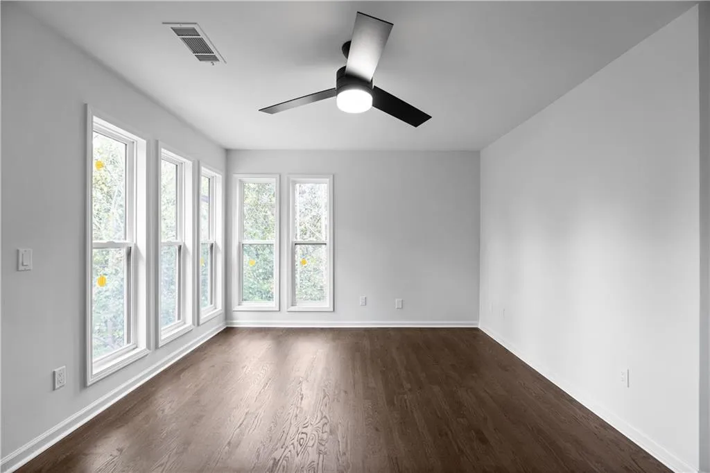 Empty room featuring dark wood-type flooring and ceiling fan