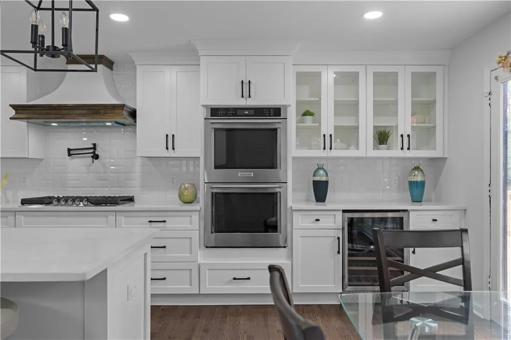 Kitchen featuring dark wood-type flooring, tasteful backsplash, white cabinetry, and appliances with stainless steel finishes
