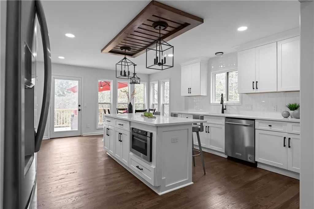 Kitchen featuring stainless steel appliances, a kitchen island, white cabinetry, a wealth of natural light, and dark wood-type flooring