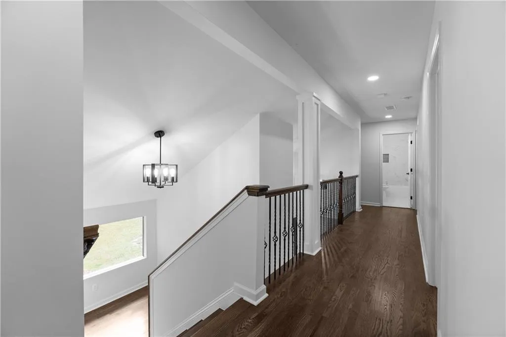 Hallway featuring dark wood-type flooring and a chandelier