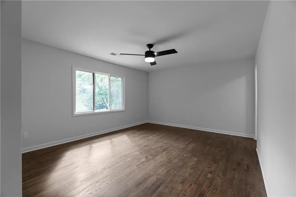 Unfurnished room featuring ceiling fan and dark hardwood / wood-style floors