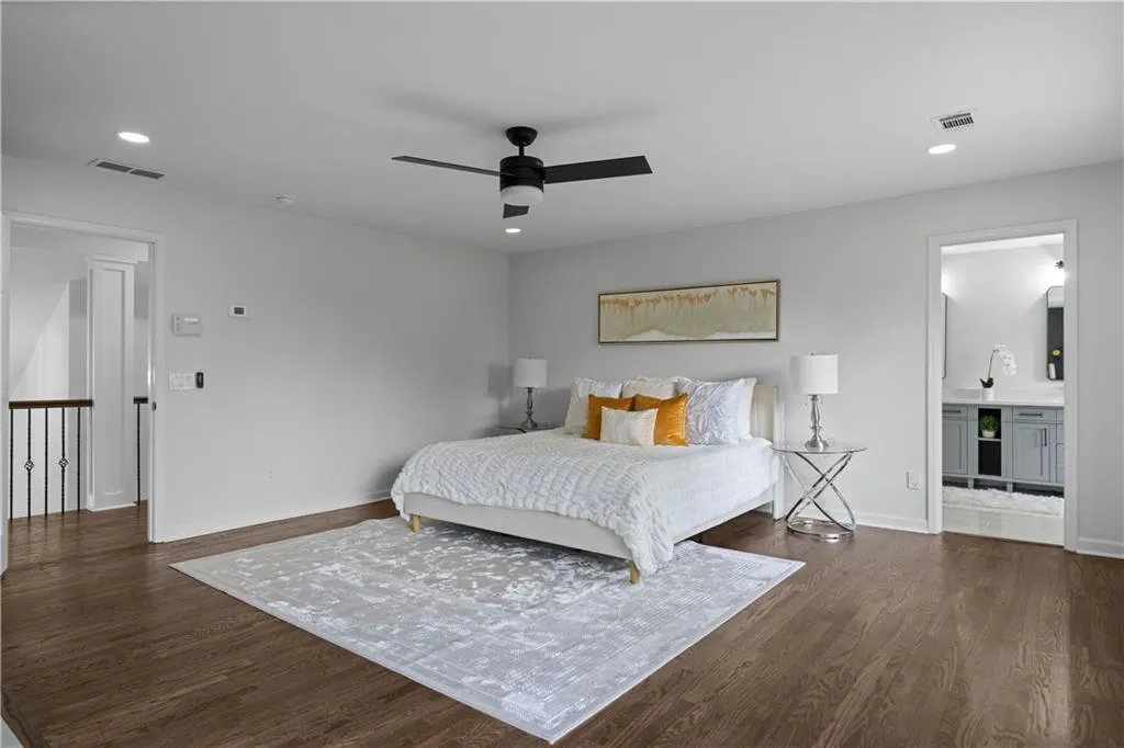 Bedroom with ceiling fan, dark hardwood / wood-style floors, and connected bathroom