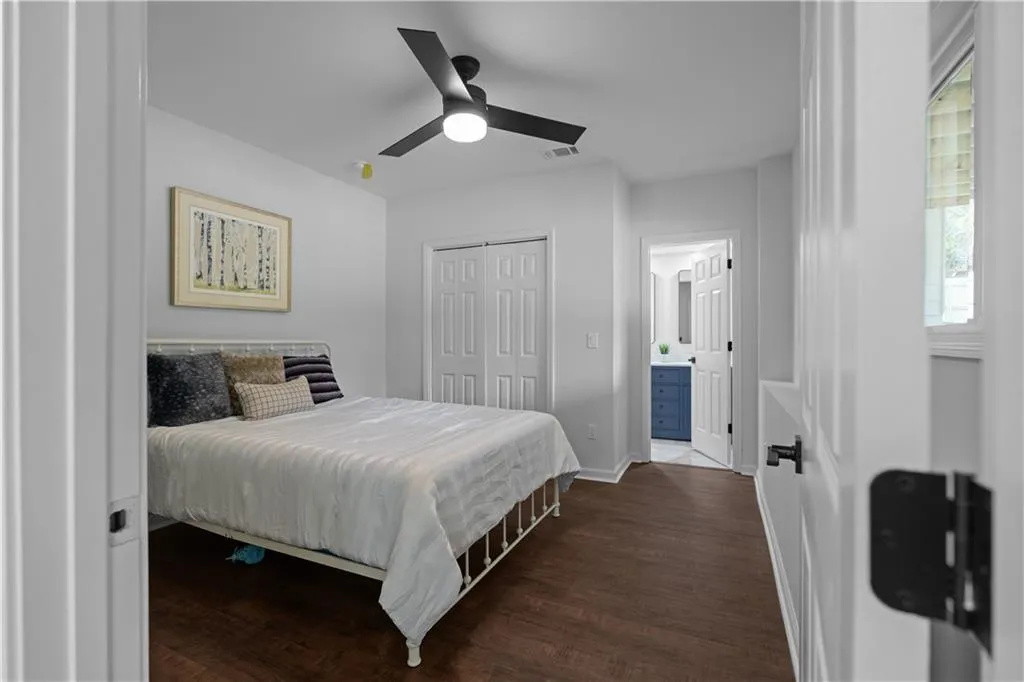 Bedroom featuring dark hardwood / wood-style flooring, a closet, ceiling fan, and ensuite bath