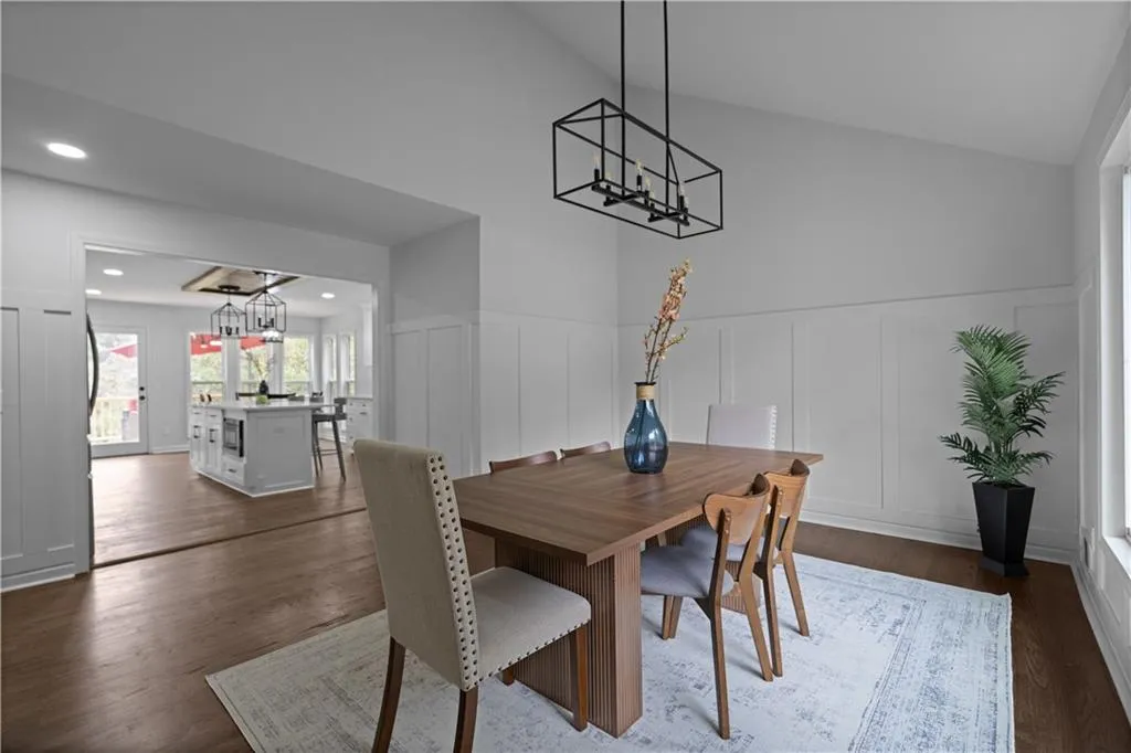 Dining room with dark hardwood / wood-style flooring, a chandelier, and lofted ceiling