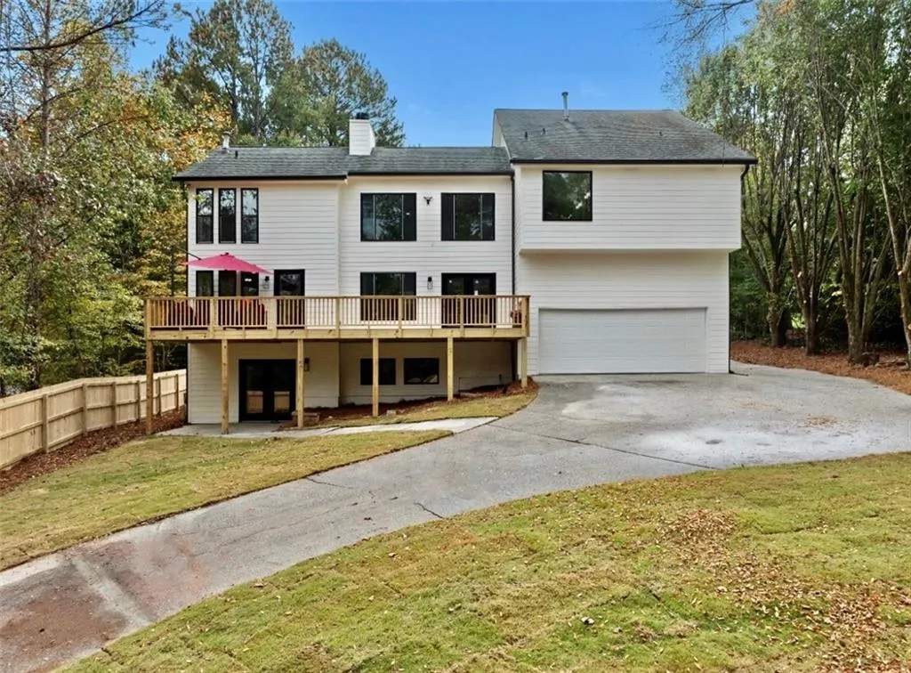 Rear view of property with a lawn, a garage, and a deck