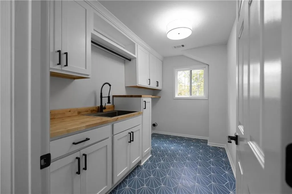 Clothes washing area featuring dark tile patterned flooring and sink