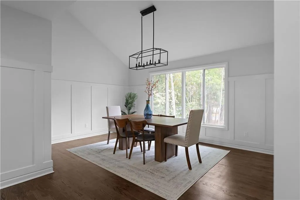 Dining area with high vaulted ceiling, dark hardwood / wood-style flooring, and a notable chandelier