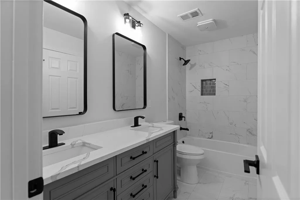 Full bathroom featuring vanity, tiled shower / bath combo, and toilet