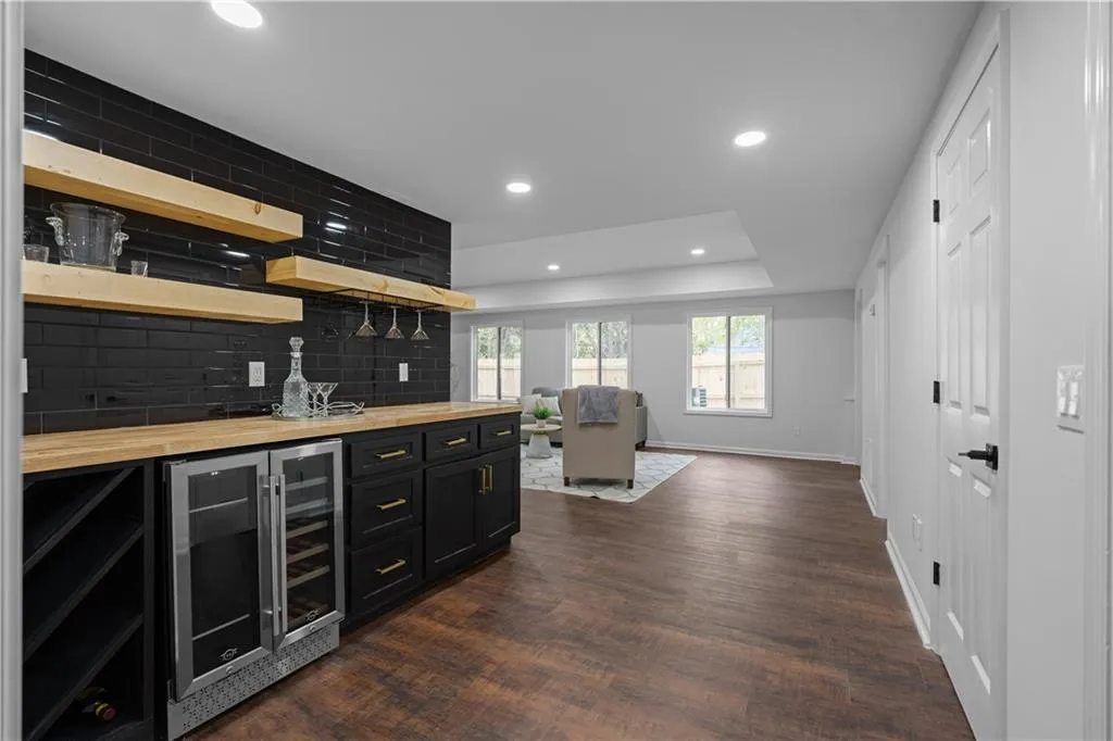 Bar featuring wooden counters, backsplash, a raised ceiling, dark wood-type flooring, and beverage cooler