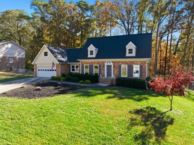 Traditional-style residence featuring brick siding, a dark roof, and light-colored dormer windows