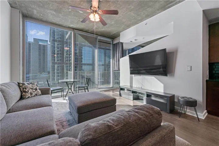 Living room featuring a wall of windows, wood finished floors, and a ceiling fan