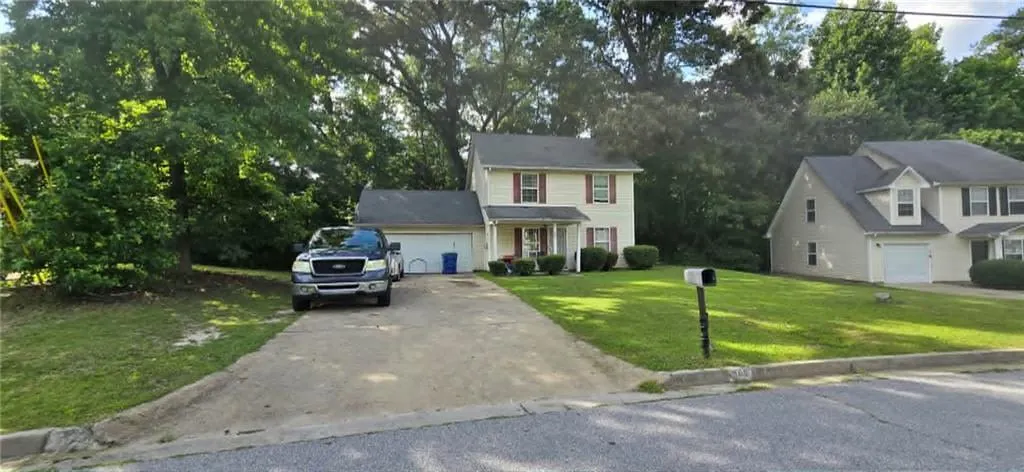 Two-story residence with a beige exterior, red window shutters, and a covered front porch
