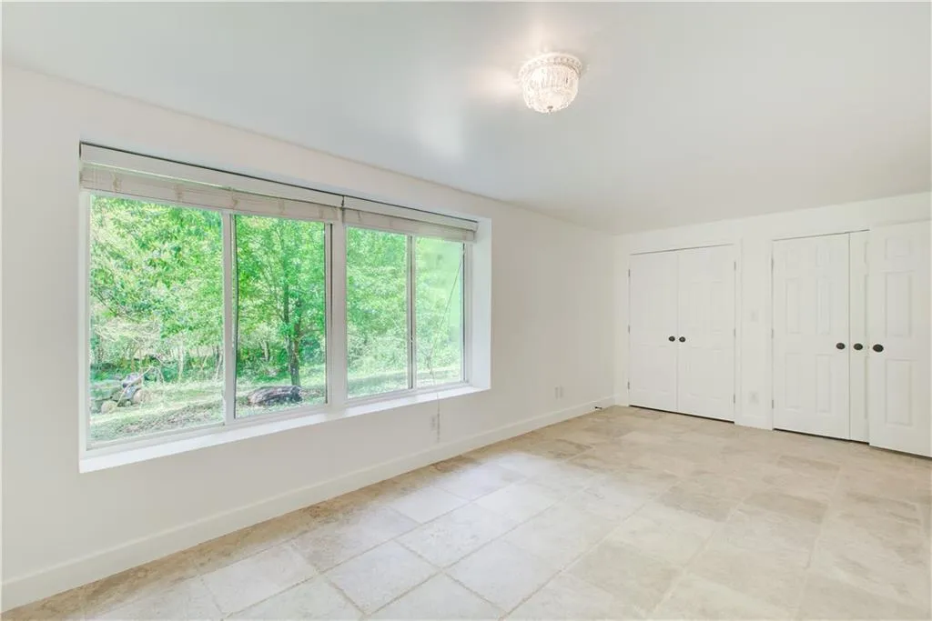 Unfurnished bedroom with multiple windows, multiple closets, and baseboards