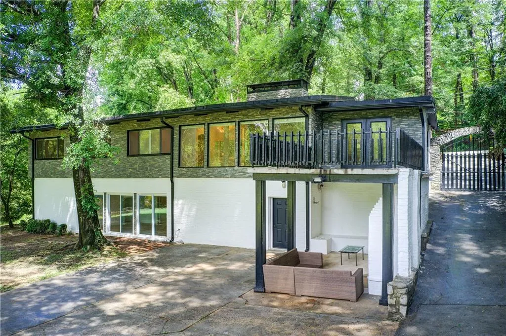 Rear view of house with a patio, brick siding, and a balcony