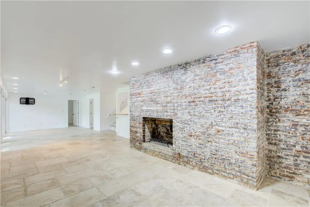 Unfurnished living room with a fireplace, stairs, recessed lighting, light stone finish flooring, and baseboards