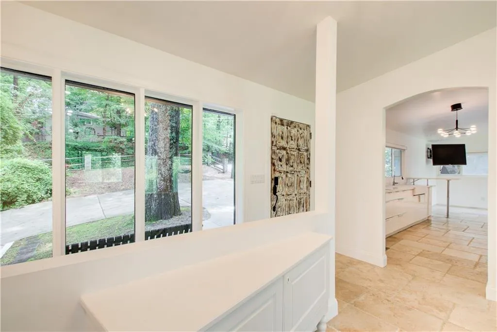 Hallway with plenty of natural light, stone tile flooring, baseboards, and arched walkways