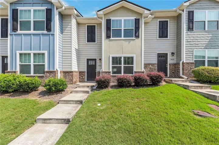 Townhome exterior featuring varied siding materials, brick accents, and dark entry doors