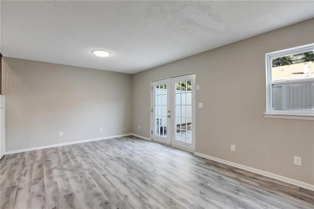 Empty room with french doors, healthy amount of natural light, a textured ceiling, and light wood-style floors