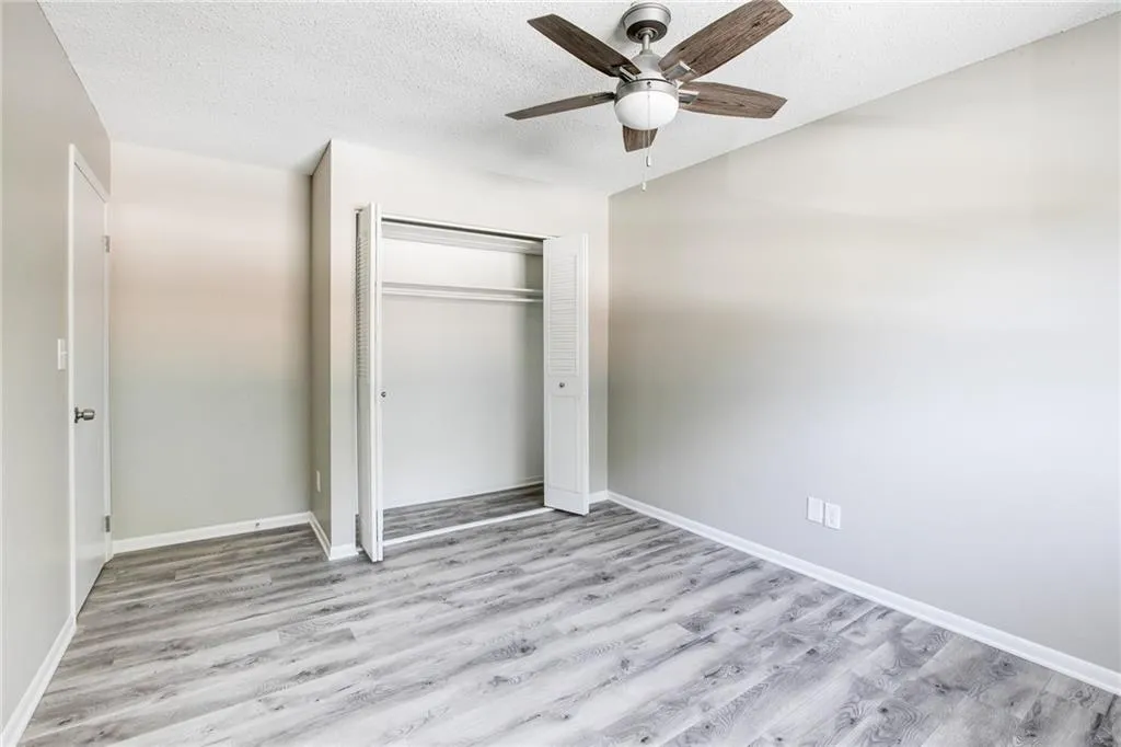 Unfurnished bedroom featuring light wood-type flooring, a textured ceiling, a ceiling fan, and a closet
