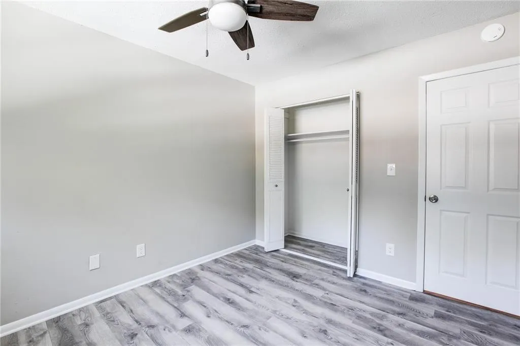 Unfurnished bedroom with wood finished floors, a closet, ceiling fan, and a textured ceiling