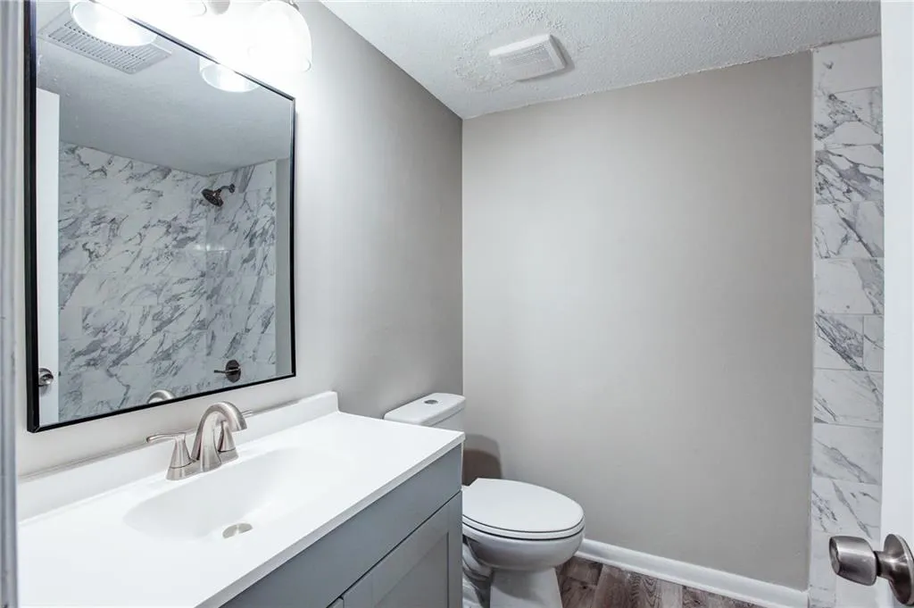 Full bath with vanity, a textured ceiling, dark wood-style flooring, and a shower