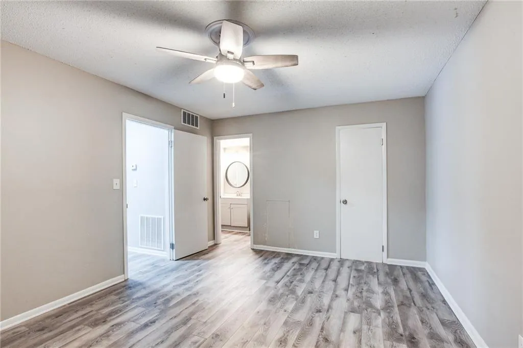 Unfurnished bedroom featuring light wood finished floors, a ceiling fan, a textured ceiling, and connected bathroom