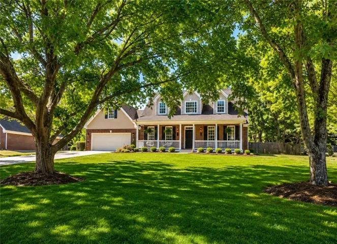 Colonial-style residence featuring a brick and siding exterior, a full-width covered porch with white railings, and multiple dormer windows
