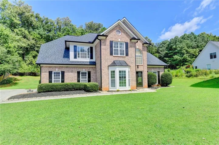Brick exterior with dark shutters, gabled roof, and bay window