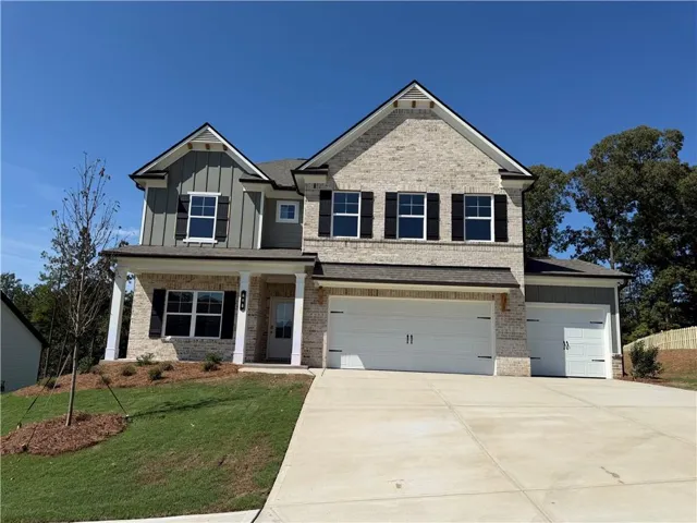 Two-story residence featuring a brick and vertical siding exterior, a front porch with white columns, and a multi-car garage