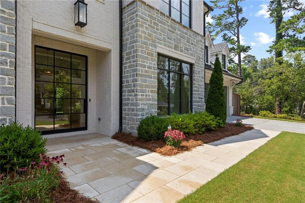 Stone and brick facade with black-framed windows and a complementary paver walkway