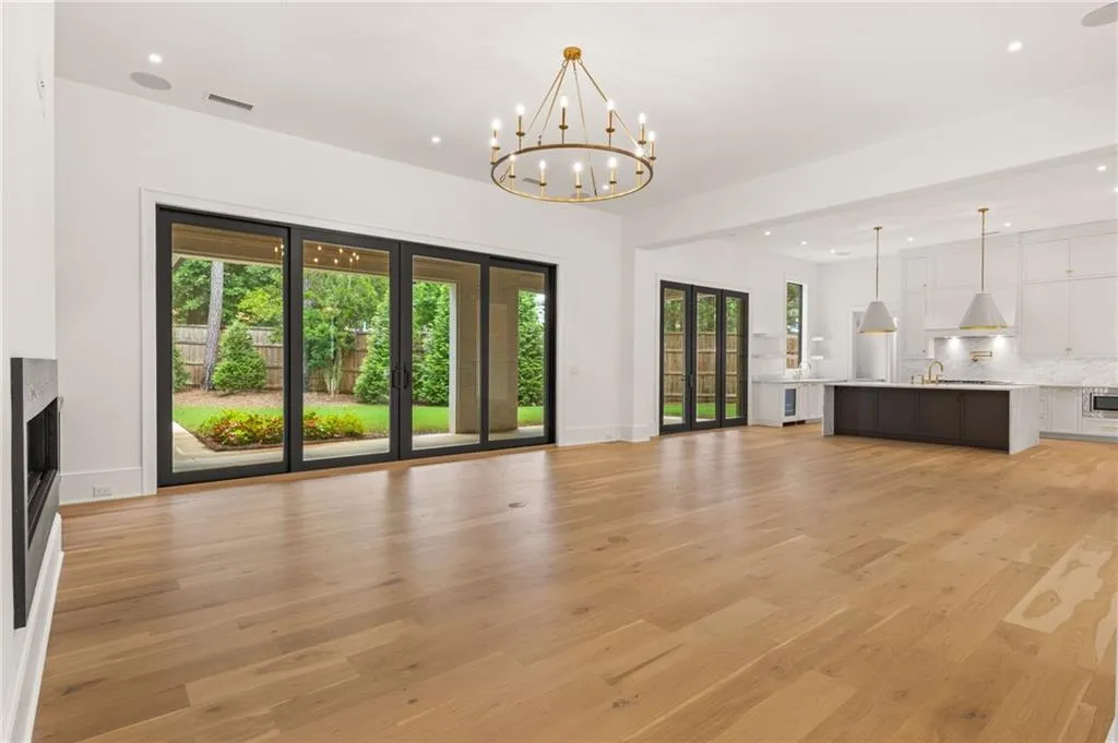 Expansive main living area featuring wide-plank wood-finish flooring, a contemporary fireplace, and a gold-tone chandelier