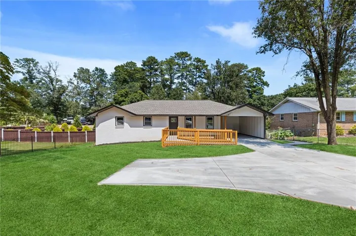 Single-story residence featuring a wood deck, carport, and a concrete driveway