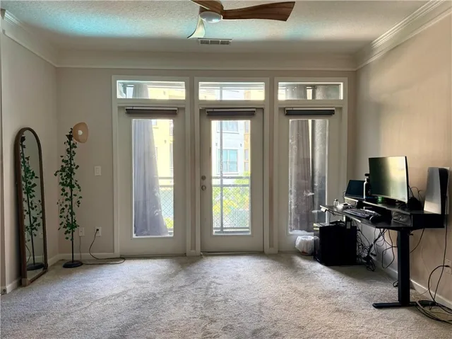 Room featuring a triple glass door entry, crown molding, and a ceiling fan with wood-finish blades