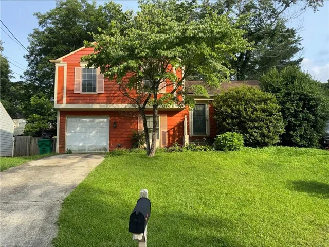 Two-story residence featuring orange siding and a prominent front yard